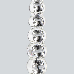 Dildo en verre transparent composé de formes sphériques alignées, présenté verticalement sur fond blanc, avec une finition lisse et brillante.