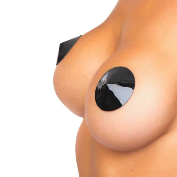 Gros plan sur une poitrine portant des cache-tétons ronds noirs à finition vernie, surface brillante et lisse, portés directement sur la peau.