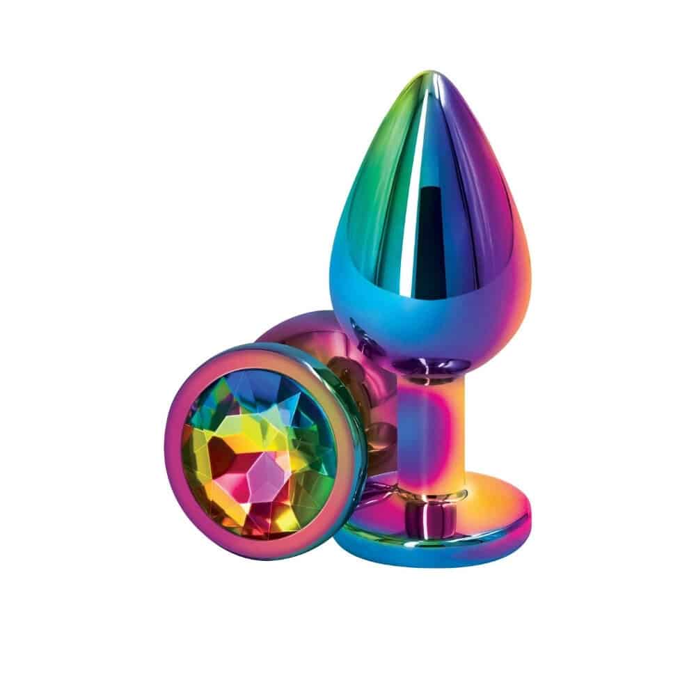 Plug anal en cristal multicolore avec base décorative en forme de cœur facetté, présenté sur fond sombre avec effets lumineux et reflets irisés.