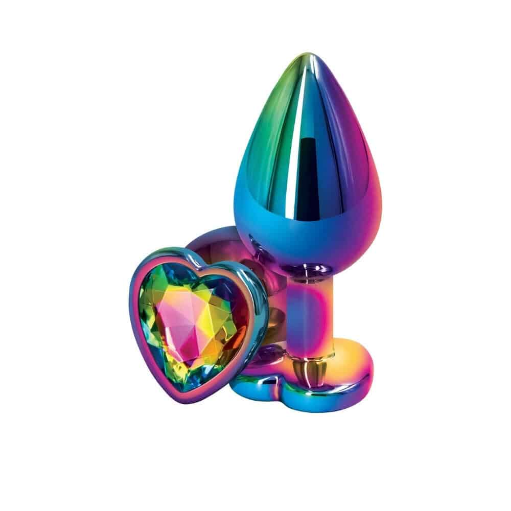 Plug anal en cristal multicolore avec base décorative en forme de cœur facetté, présenté sur fond sombre avec effets lumineux et reflets irisés.