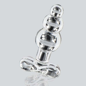 Plug anal en verre transparent à forme facettée avec base évasée, présenté sur fond clair, finition brillante, sélection Brigade Mondaine Paris.