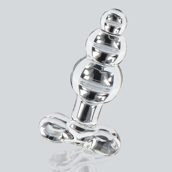 Plug anal en verre transparent à forme facettée avec base évasée, présenté sur fond clair, finition brillante, sélection Brigade Mondaine Paris.