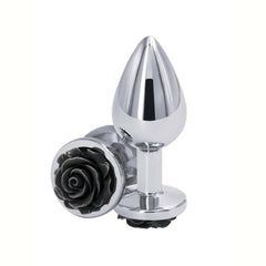 Plug anal en métal poli avec base décorative en forme de rose noire, posé sur fond blanc, sélection Brigade Mondaine Paris.