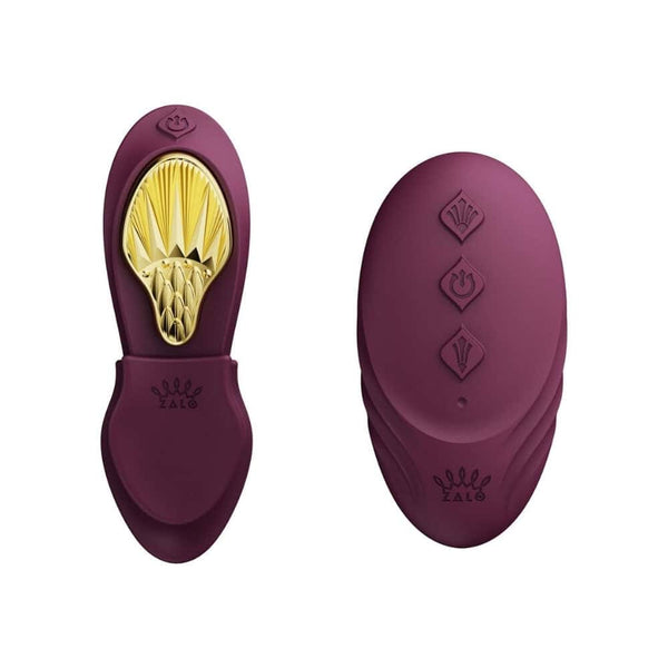 Vibromasseur portable de couleur prune avec détails dorés, design ergonomique et commandes intégrées, présenté sur fond blanc, sélection Brigade Mondaine Paris.