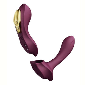 Vibromasseur portable de couleur prune avec détails dorés, design ergonomique et commandes intégrées, présenté sur fond blanc, sélection Brigade Mondaine Paris.