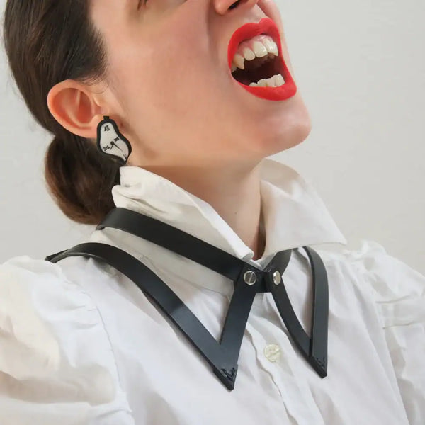 Vue rapprochée du choker 86647 en cuir noir porté sur une chemise blanche avec col, mettant en avant le design inspiré du col de chemise. La femme porte du rouge à lèvres rouge et affiche des dents légèrement vampiriques, ajoutant une touche audacieuse à son look.