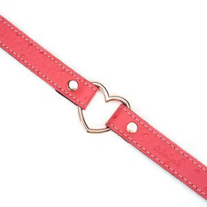 Choker Cœur en cuir rose embossé peau d’autruche avec cœur central en métal or rose. Boucle métallique robuste. Accessoire fétichiste séduisant et affirmatif. Ajustable pour un confort parfait.