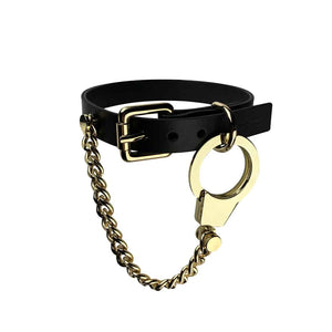 Collier Menottes chaines et cuir de la marque ELF ZHOU LONDON. le collier est attaché autour du cou du mannequin. La partie en cuir du collier est attachée et la chaine en or rattachée au collier par la menotte en or pend.