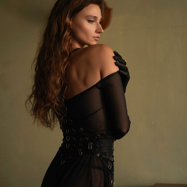Robe longue en résille noire drapé fluide avec une traîne subtile manches longues avec gants intégrés avec bretelles amovibles inclus paire avec finitions dorées, l’autre en noir porté avec un harnais noir en élastique travail complexe dans le dos détails en anneaux dorés, les sangles ajustables et les attaches multiples