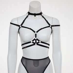 Harnais bondage Moon FLASH en sangles noires avec anneaux dorés, vue à plat sur fond blanc, design graphique et ajustable - Brigade Mondaine Paris