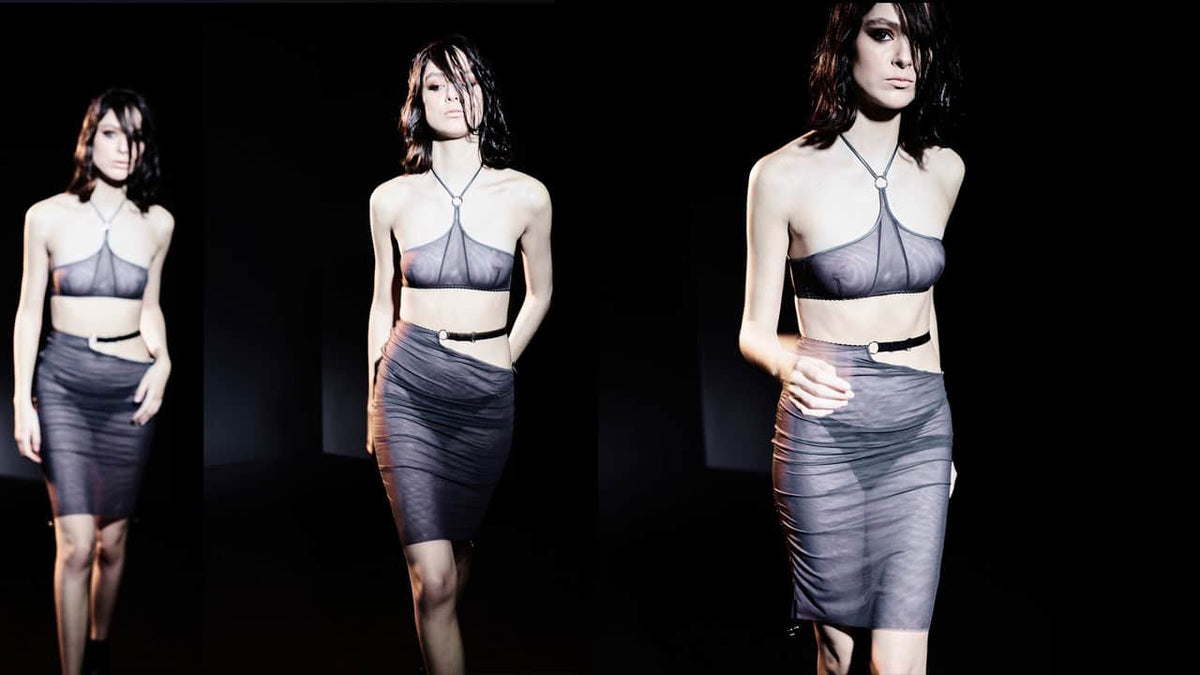 Ensemble de lingerie de luxe comprenant une jupe mi-longue en tulle gris fumé avec des bandes élastiques en satin et des anneaux argentés soulignant les plis. Le top bandeau assorti présente un design épuré avec un anneau argenté au centre et une coupe ajustable, parfait pour un confort et une allure raffinés.