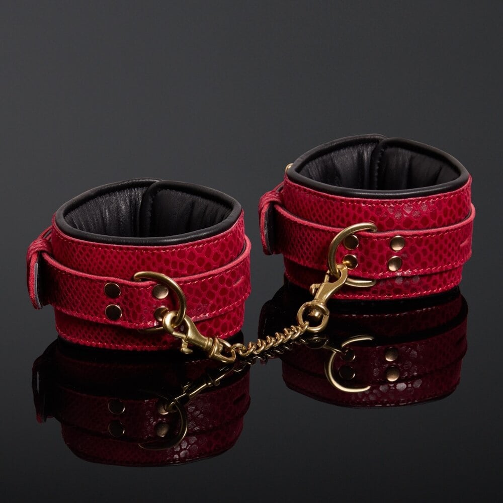 Menottes en cuir embossé serpent rouge avec finitions dorées et intérieur en cuir de veau noir, offrant confort et maintien avec un design visuellement saisissant.
