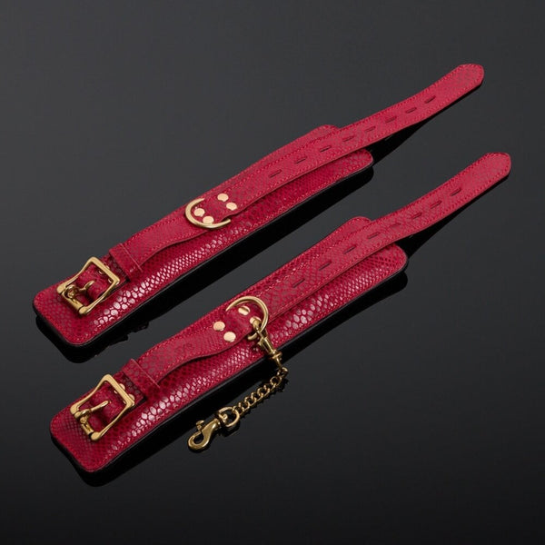 Menottes en cuir embossé serpent rouge avec finitions dorées et intérieur en cuir de veau noir, offrant confort et maintien avec un design visuellement saisissant.