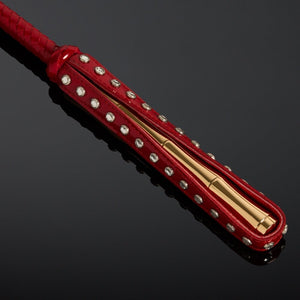 Cravache en vernis rouge HOUSE OF SXN avec manche rigide et extrémité plate, accessoire BDSM haut de gamme proposé par Brigade Mondaine Paris.