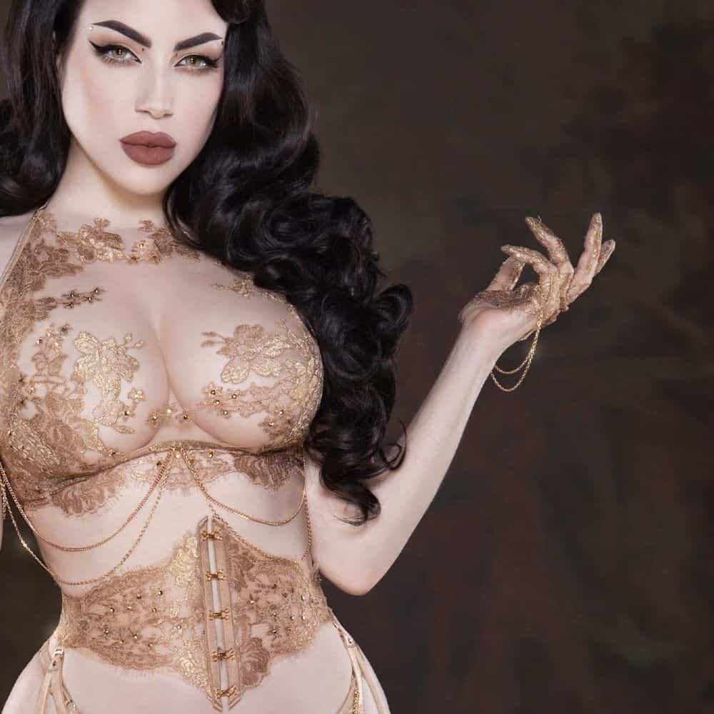 Le corset et le soutien-gorge long AIMÉE sont réalisés à la main avec de la dentelle Leavers française en or rosé, du tulle ultra-transparent et des cristaux scintillants. Leur structure en baleines souples et leur laçage arrière assurent un ajustement personnalisé. Les mitaines assorties, ornées de cristaux et de chaînes dorées, apportent une touche précieuse. Chaque pièce est confectionnée à Barcelone avec des matériaux de luxe, notamment la viscose, le nylon et le polyester, et de la quincaillerie plaqué