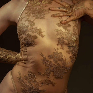 Le body licou AMMALIE sublime la silhouette avec son effet seconde peau et son éclat doré subtil. Confectionné à la main en maille illusion ultra-transparente, il épouse le corps avec finesse. Son appliqué en dentelle Leavers française en or rosé, découpé et cousu à la main, ajoute une touche précieuse. Les bretelles dorées réglables et les accessoires plaqués or 24 carats assurent un ajustement parfait. Pour un confort optimal, l’intérieur est doublé en coton de bambou biologique.