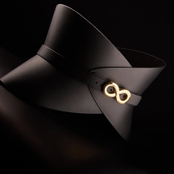 Corset ceinture HUDIA IINFYNII en cuir noir avec fermoir métallique infini porté sur un tailleur noir, accessoire structurant et graphique proposé par Brigade Mondaine Paris