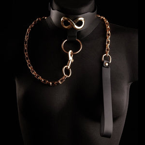 Le collier laisse SEVERA de IINFYNII associe cuir noir et chaîne métallique dorée dans une construction affirmée et structurante. Pensé comme une pièce de corps forte, il se compose d’un collier en cuir orné d’un symbole métallique signature, prolongé par une chaîne articulée reliée à un anneau central. Ajustable, il peut se porter seul ou intégré à une silhouette complète, entre bijou de contrainte et accessoire sculptural. Une pièce graphique, directe, conçue pour celles et ceux qui envisagent le corps co
