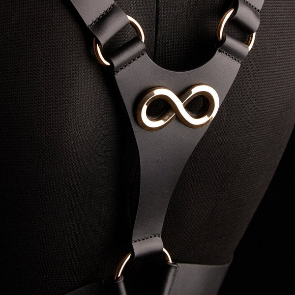 Harnais TRISCA IINFYNII en sangles noires avec boucles dorées et détail central, accessoire structurant porté sur le buste proposé par Brigade Mondaine Paris