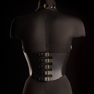 Corset Bondage HOSTIA IINFYNII noir avec sangles et anneaux métalliques porté sur un top en mesh, pièce structurée proposée par Brigade Mondaine Paris