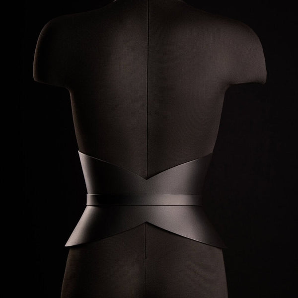 Corset ceinture HUDIA IINFYNII en cuir noir avec fermoir métallique infini porté sur un tailleur noir, accessoire structurant et graphique proposé par Brigade Mondaine Paris