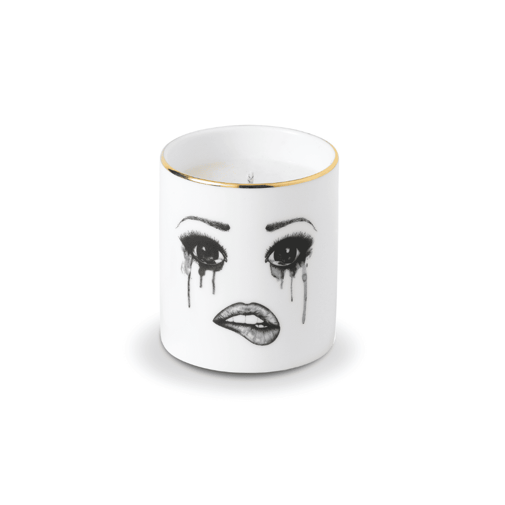 Une bougie parfumée en porcelaine chinoise blanche arbore un visage mélancolique, soigneusement tracé en feutrine. Ce visage exprime la tristesse avec des larmes coulant et un maquillage qui se fond, tandis que la lèvre inférieure est délicatement mordue, créant une composition émouvante et artistique.