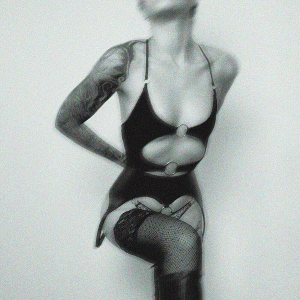 Lingerie en jersey extensible alliant douceur et provocation. Coupe ouverte avec anneaux métalliques argentés, élastique picot, noué au dos et bretelles réglables pour un ajustement personnalisé.