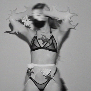 Lingerie en tulle noir à double couche, noué derrière la nuque par un élastique spaghetti. Anneaux métalliques argentés pour une touche espiègle et élégante.