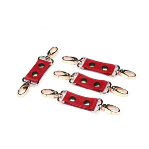 Hogtie Crimson Desire de la marque Liebe Seele, composé de sangles en cuir rouge reliées par un anneau central et des mousquetons dorés, présenté sur fond clair dans l’univers Brigade Mondaine Paris.