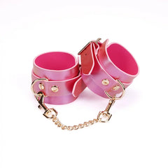 Menottes Chevilles Lustre Rosa LIEBE SEELE en cuir rose irisé avec doublure rose, rivets et chaîne métallique dorée, présentées sur fond blanc