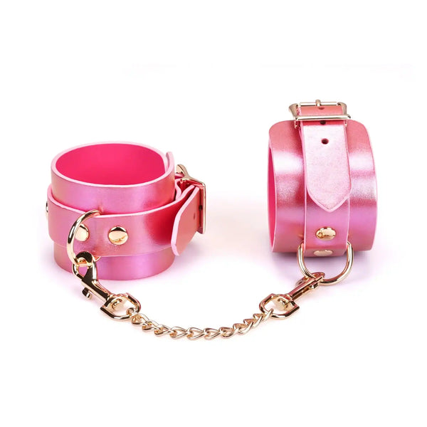 Menottes Chevilles Lustre Rosa LIEBE SEELE en cuir rose irisé avec doublure rose, rivets et chaîne métallique dorée, présentées sur fond blanc