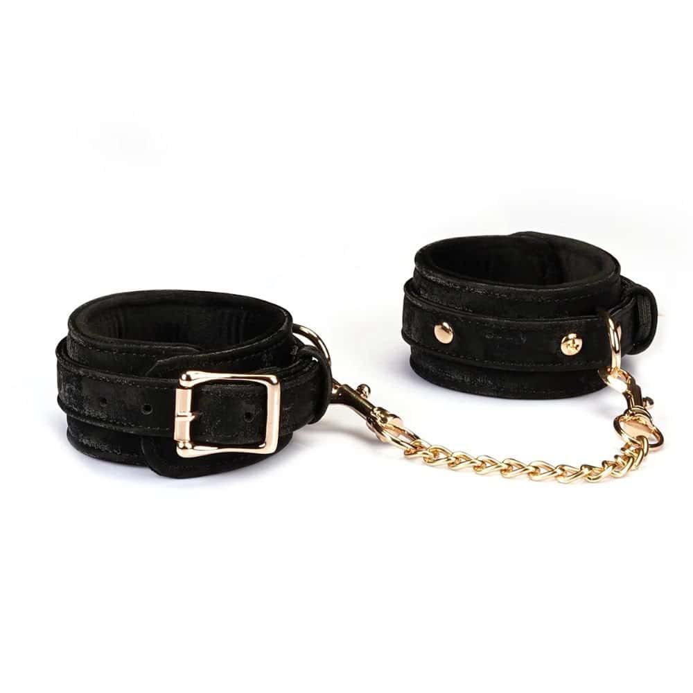 Menottes Boudoir Amor en cuir végétalien noir avec finitions dorées. Anneau en D robuste, boucles métalliques ajustables, clips à dégagement rapide. Accessoire BDSM de luxe pour un contrôle total et raffiné.