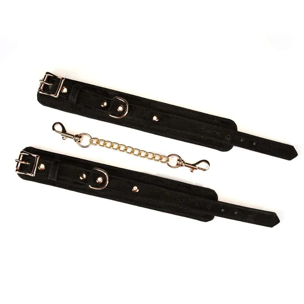 Menottes Boudoir Amor en cuir végétalien noir avec finitions dorées. Anneau en D robuste, boucles métalliques ajustables, clips à dégagement rapide. Accessoire BDSM de luxe pour un contrôle total et raffiné.