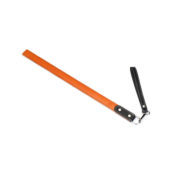 Règle de fessée en cuir orange LIEBE SEELE avec poignée et dragonne, coutures contrastées, présentée sur fond blanc