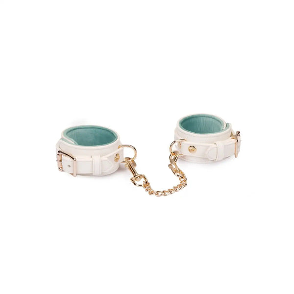 Menottes Boudoir Amor de la marque Liebe Seele, en cuir clair avec chaîne et mousquetons dorés, présentées à plat sur fond clair dans l’univers Brigade Mondaine Paris.