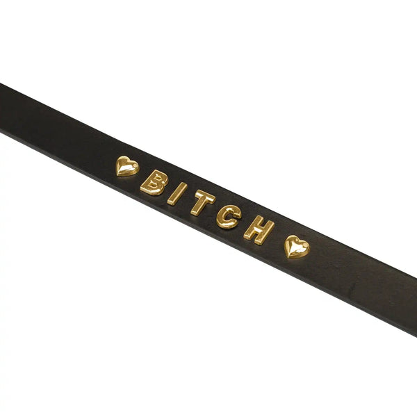 Collier en cuir noir LIEBE SEELE avec inscription Bitch en lettres dorées et boutons pression réglables, présenté sur fond blanc