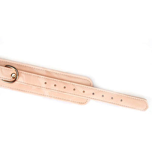 Menottes Boudoir Amor en similicuir vegan rose pastel et noir. Finitions dorées, anneau en D pour fixation. Boucles ajustables et clips à dégagement rapide pour sécurité et confort. Idéales pour des jeux de soumission élégants.