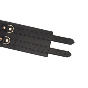 Ceinture de bondage en cuir noir de la collection Dark Secret. Fabriquée à la main avec des finitions dorées et deux anneaux en D pour fixation. Accessoire de domination luxueux et raffiné.