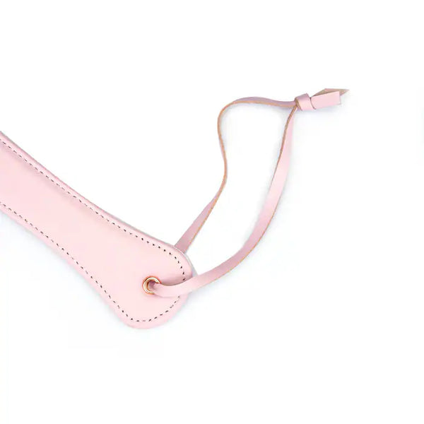 Paddle en cuir rose de la collection Fairy, confectionné en cuir d'agneau blanc et rose avec accents or rose. Un accessoire BDSM raffiné pour des jeux de fessée contrôlés et élégants.
