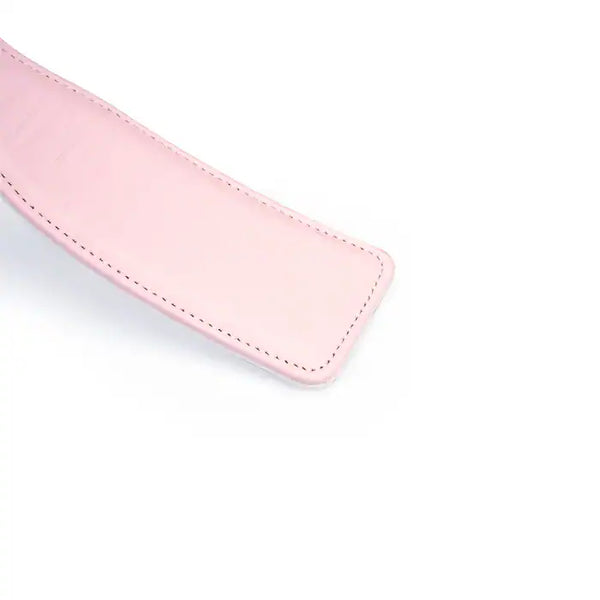 Paddle en cuir rose de la collection Fairy, confectionné en cuir d'agneau blanc et rose avec accents or rose. Un accessoire BDSM raffiné pour des jeux de fessée contrôlés et élégants.