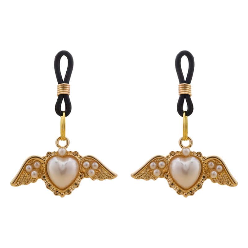 Pinces pour tétons Angel de la marque Liebe Seele, ornées de cœurs ailés dorés et de perles, reliées par des attaches noires, présentées sur fond clair dans l’univers Brigade Mondaine Paris.