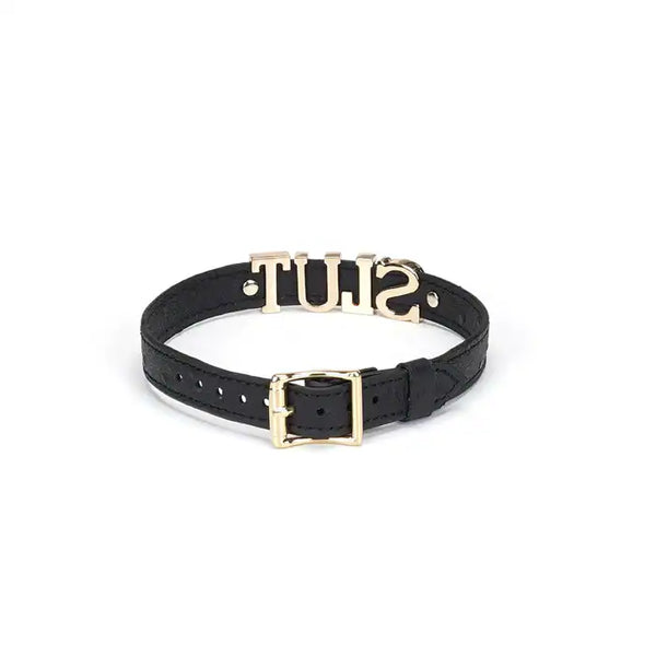 Choker en cuir noir embossé avec lettres argentées SLUT et finitions dorées. Accessoire ajustable, souple et confortable, parfait pour jeux BDSM et tenues fétichistes.