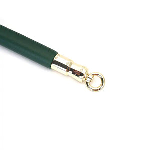 Barre d'écartement en cuir vert et bois d'eucalyptus, avec attaches métalliques dorées. Accessoire BDSM élégant pour une immobilisation précise et contrôlée, parfait pour la collection Mossy Chic.