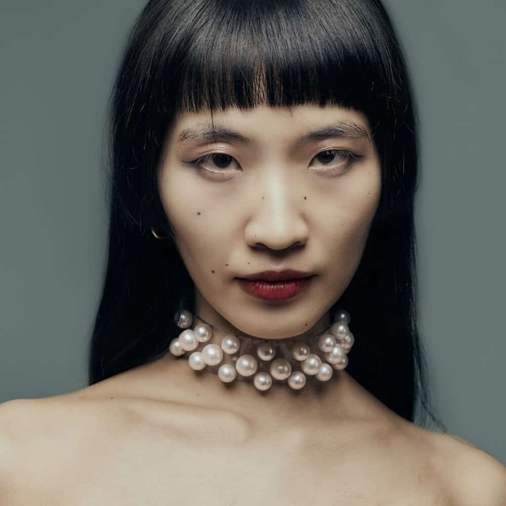 Modèle portant le Boudoir Choker Perlensau avec perles blanches montées sur base transparente, proposé par Brigade Mondaine Paris.