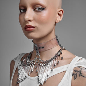 Modèle portant le Cosmic Choker Perlensau en matière transparente avec chaînes métalliques et pampilles suspendues, proposé par Brigade Mondaine Paris.