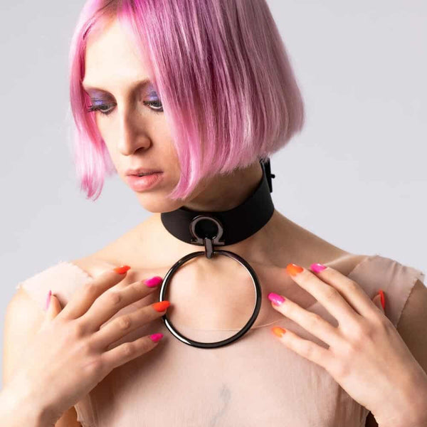 Modèle portant le choker Divine Perlensau en cuir noir avec large anneau métallique suspendu, proposé par Brigade Mondaine Paris.