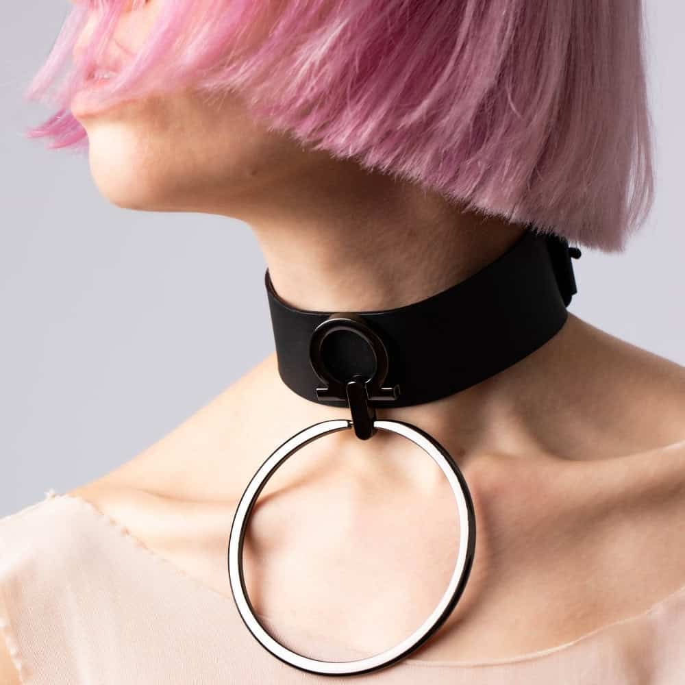 Modèle portant le choker Divine Perlensau en cuir noir avec large anneau métallique suspendu, proposé par Brigade Mondaine Paris.