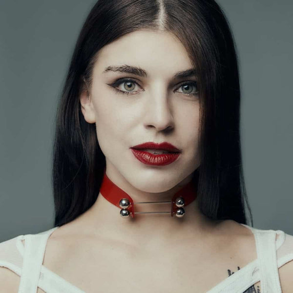 Modèle portant le Industrial Choker rouge Perlensau en cuir avec tiges métalliques et sphères argentées, proposé par Brigade Mondaine Paris.