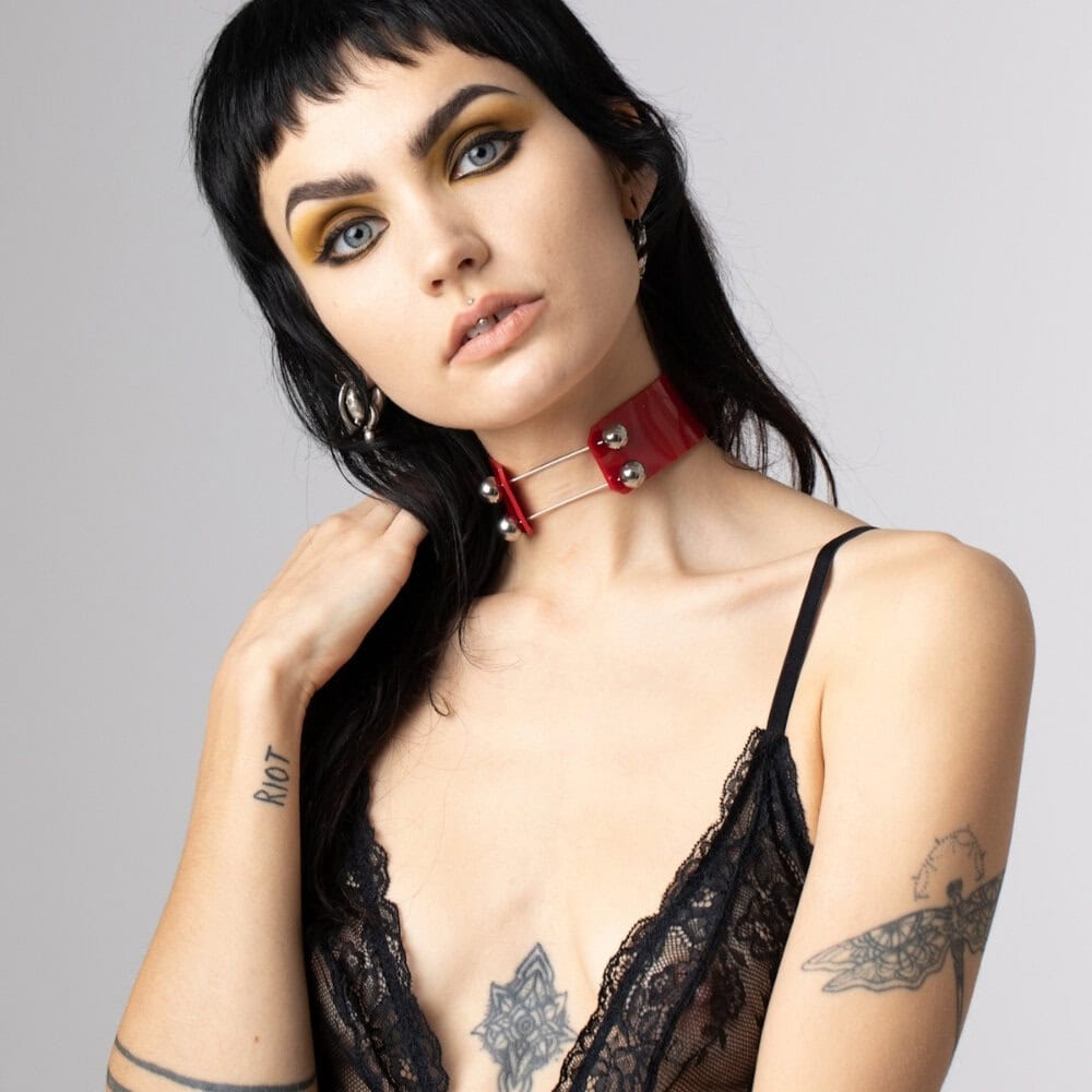 Modèle portant le Industrial Choker rouge Perlensau en cuir avec tiges métalliques et sphères argentées, proposé par Brigade Mondaine Paris.