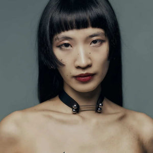 Modèle portant le Industrial Choker Perlensau en cuir noir avec éléments métalliques argentés, proposé par Brigade Mondaine Paris.